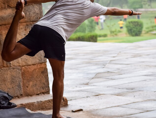 Inspired Indian young man doing yoga asanas in Lodhi Garden Park, New Delhi, India. Young citizen...