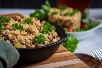 Dirty rice, a classic cajun dish made with ground pork, celery, onions, garlic scapes, and green pepper. Topped with parsley.