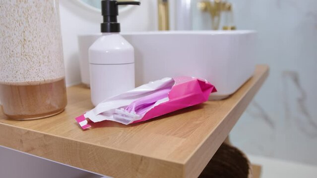 Hand of young woman grabbing razor blade in modern bathroom, static view