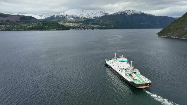 Ferry to Stranda in More and Romsdal Norway - Ferry named Volda is underway with Stranda town seen in background below snow capped mountain