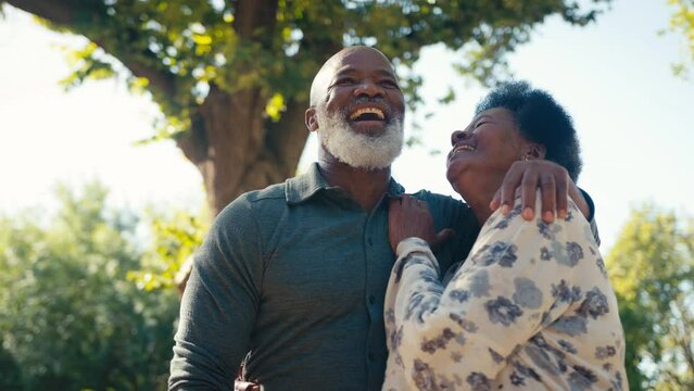 Loving senior couple outdoors in garden hugging and smiling at camera  - shot in slow motion