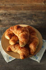 Fresh croissant in a wooden plate on table - 617017452