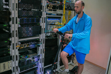 A man stands on an electric scooter in a server room. A technician drives up to the server racks of the data center in an electric vehicle.