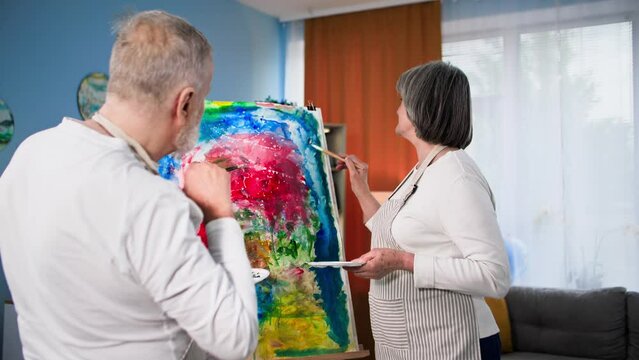 creative hobby, talented pensioners are fond of painting a modern picture using brushes and paints on canvas at home