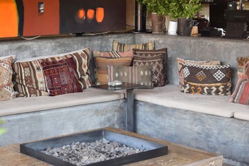 sitting area with cushions and colorful pillow designs on open exterior patio with outdoor fireplace