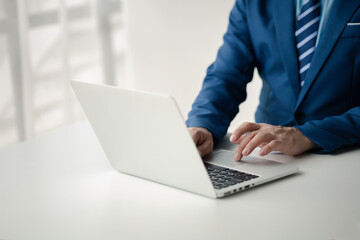 Person typing on laptop keyboard, businessman working on laptop, he is typing messages to colleagues and making financial information sheet to sum up the meeting.