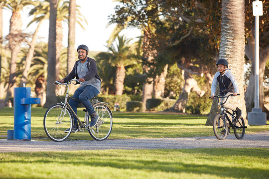 Father and son (12-13) riding bicycles in park