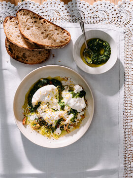 Overhead view of burrata with green pesto and bread