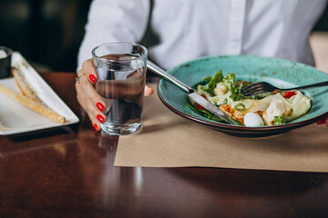 Woman eating bowl of salad with a glass of water