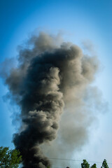 Emergency helicopter recharging water to extinguish a forest fire thick black smoke rises into the...