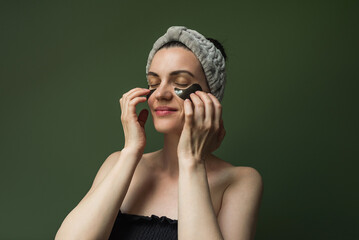 A woman with black collagen pads under her eyes, with a soft cosmetic bandage on her head. Mature...