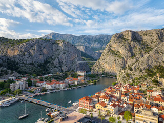 Amazing panoramic view of the picturesque town of Omish in Croatia, the cliffs, the old houses with red roofs, the historic buildings and the river flowing into the turquoise Adriatic Sea