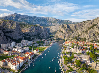 Amazing panoramic view of the picturesque town of Omish in Croatia, the cliffs, the old houses with red roofs, the historic buildings and the river flowing into the turquoise Adriatic Sea