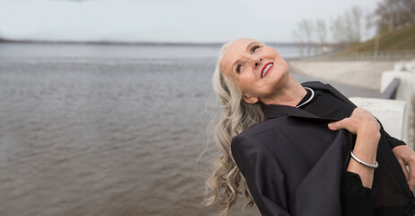 lifestyle portrait senior woman  with gray hairrelaxes  wearing a black suit on the seashore. spends time in nature. copy space. greyhairdontcare