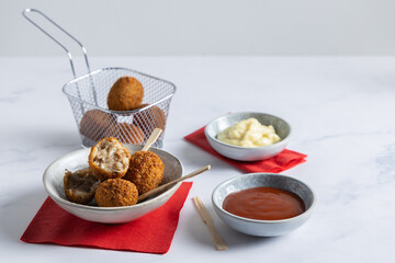 Fried meatballs in a bowl with ketchup on the side.