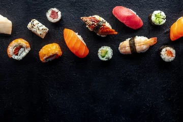 Photo sur Plexiglas Bar à sushi Sushi, shot from the top. Rolls, maki, nigiri on a black slate background, Japanese food. Salmon, eel, shrimp, tuna etc with rice, with a place for text
