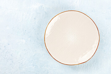 An empty white plate with a gold rim, shot from above on a slate background with a place for text