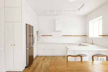 Modern minimal kitchen design. Modern kitchen interior. Stylish white kitchen cabinets with brass knobs, faucet, granite island and appliances in new scandinavian house.