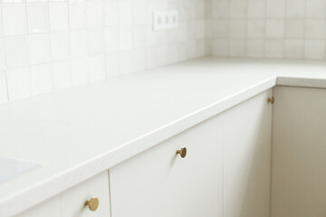 Modern kitchen interior. Stylish white kitchen cabinets with brass knobs and granite countertop...