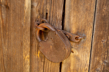 an old barn lock on a wooden door. Rusty lock