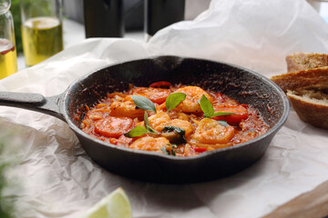 Shrimps in tomato sauce, in frying pan, close-up. Prawns in red sauce, in cast iron pan, selective focus.