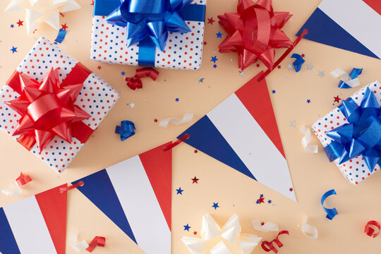 Concept for patriotic commemorations on Bastille Day. Top view photo of french national garlands, gift boxes, colorful bows, confetti on pastel beige background