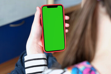Teenage girl of 12 years with backpack holds a mobile phone green screen, chromakey. Advertising....
