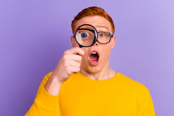 Funny man looking through magnifying glass searching or investigating something standing in sweater...