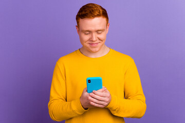 Happy young man using smart phone cellphone for calls social media mobile app isolated in violet background