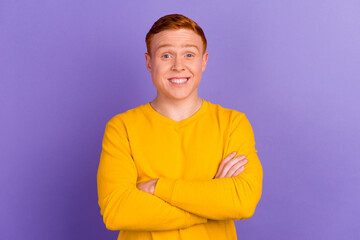 Portrait of a happy casual man standing with arms folded over violet color background and looking at camera