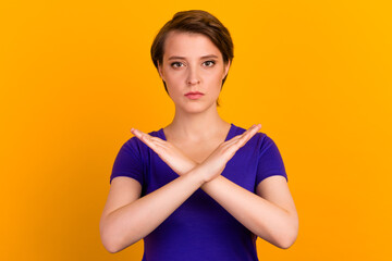 Photo of young serious woman crossed hands show no stop forbidden symbol isolated over yellow color...
