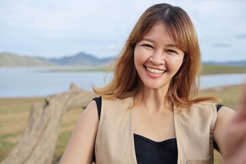 Cheerful Asian woman taking selfie on summer 