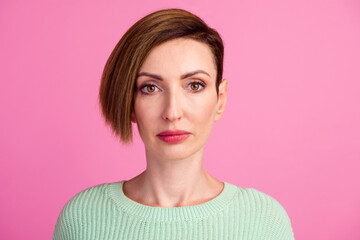 Pretty female with fair hair dressed casually looking with satisfaction at camera isolated against blank studio wall