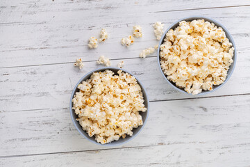 Popcorns on a blue bowls over white wooden table