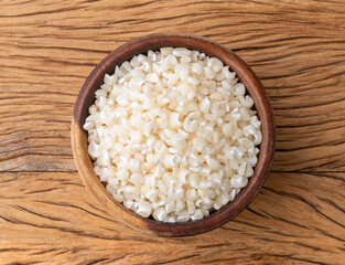 Dried canjica, hominy or white corn on a bowl over wooden table