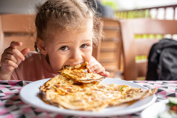 Little girl eating potato and cheese gozleme on wooden table. Traditional stuffed pancakes in Alanya, Turkey