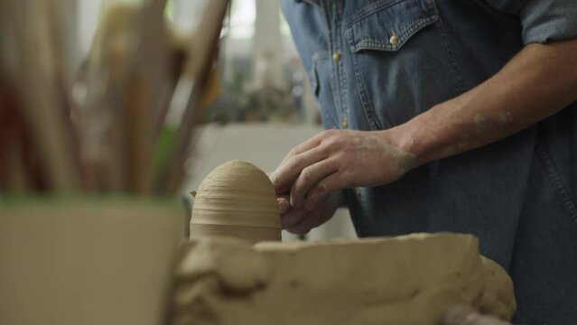 Close-up of the hands of a ceramist making clay products in a workshop on a table. A man potter works in a craft workshop. High quality 4k footage