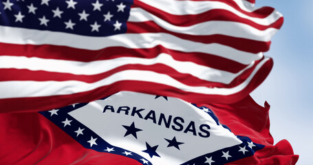 Arkansas state flags and US national flag waving in the wind on a clear day