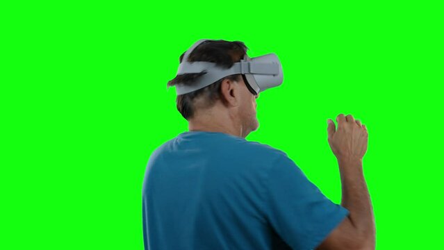 A man is amazed by his virtual reality goggles. Spins around. Green screen.  	