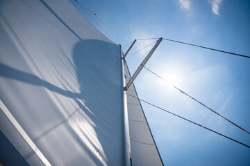 Fototapeta na wymiar Yacht sailing in an open sea. Close-up view of sails of a sailing yacht in the wind and clear sky with sun