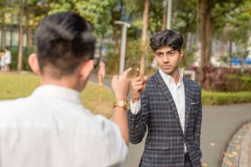 A young indian man debates or quarrels with a workmates. Finger pointing at each other. Outdoor...