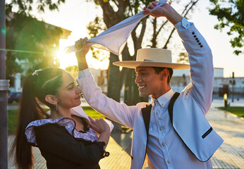 portrait young adult latin american couple dancing cueca national dance in huaso dress in the city square - obrazy, fototapety, plakaty
