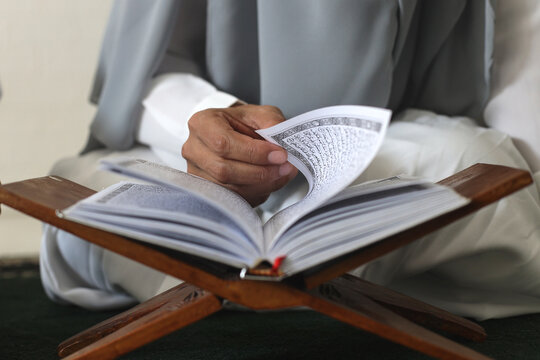 Close up hands opening koran, reciting quran