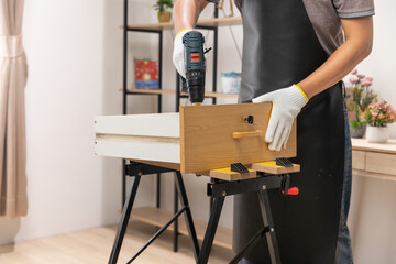 Worker repair wooden drawer of cabinet in living room. - obrazy, fototapety, plakaty