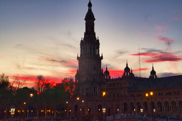 Fototapeta na wymiar Night view of the monument of plaza de spain in seville, spain. Reddish sky at sunset in the city.