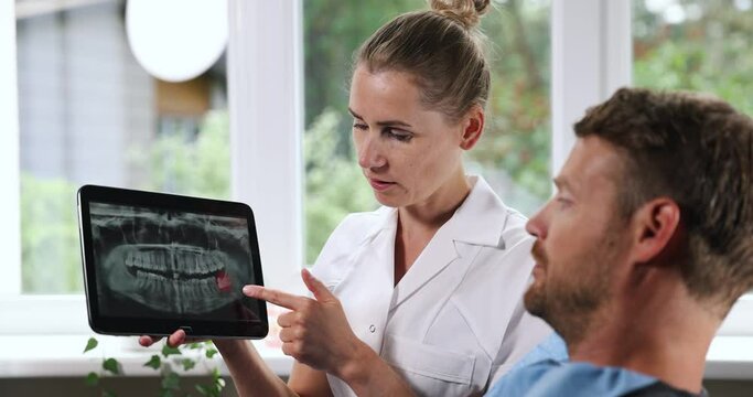 dentist explaining dental x-ray picture in digital tablet to his patient