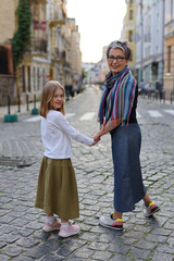 A girl with her mother or grandmother holding hands and walking through the historical part of the...