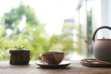 small tea cup and earthenware tea pot and cactus on wooden table outdoor drinking