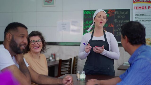 Candid restaurant scene of waitress interacting with customers in traditional Brazilian cafeteria, local business occupation, female server taking food orders