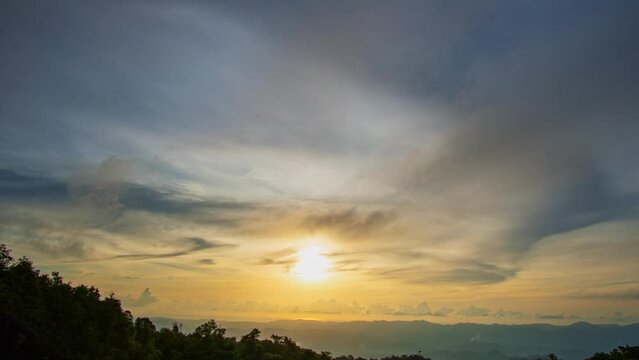 .time lapse The rays of the sun shine through the clouds above the peak..Beautiful sunset on the hill amid the mountain range with the setting sun on Phutajor hilltop at Phang Nga..Majestic landscape.